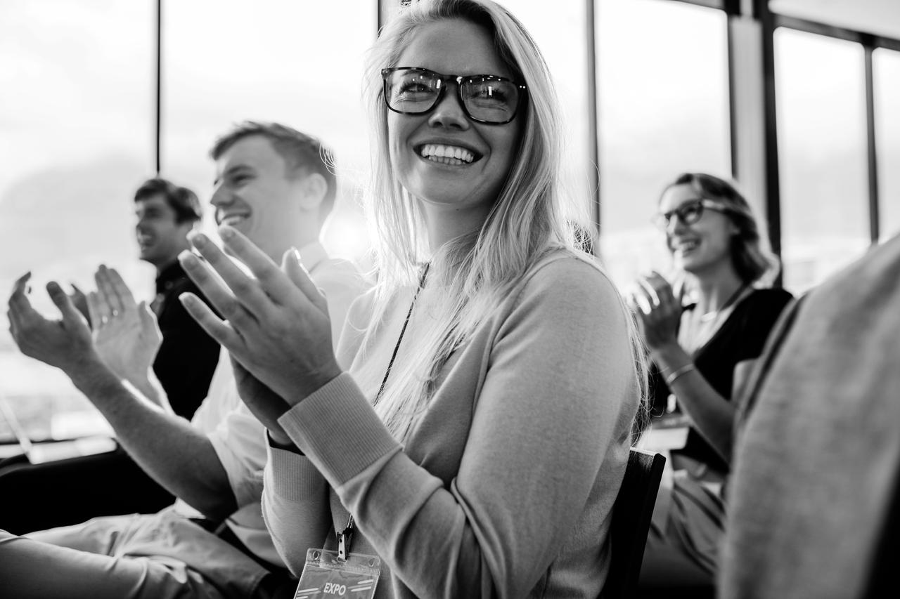 Businesspeople sitting at seminar clapping hands.
